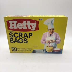 Puede incluir: Una caja amarilla de bolsas de basura de plástico Hefty. La caja presenta el logotipo de Hefty en rojo y blanco, con las palabras "SCRAP BAGS" en letras negras grandes. La caja contiene 50 bolsas, cada una de 15,2 cm x 14 cm x 30,5 cm con una tira de amarre desprendible. Un chef está ilustrado en la caja.