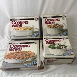 May include: Four white cardboard boxes for Corning Ware French White cookware. Each box features the Corning Ware logo, product name, and a color photograph of a white fluted dish containing food, including a casserole, pie, and round dishes.