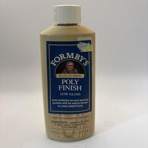 May include: A bottle of Formby's Poly Finish, low gloss, with a white cap. The label features a portrait and text that reads "Hand Rubbed Poly Finish". The bottle contains 8 fl oz (1/2 pt) or 237 mL of product.