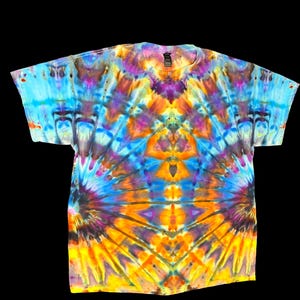 May include: A vibrant tie-dye t-shirt with a kaleidoscope of colors, including blue, purple, orange, and yellow. The shirt features a crew neck and short sleeves, perfect for casual wear. The tie-dye pattern creates a unique and eye-catching design.