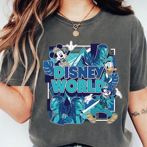 Puede incluir: Camiseta gris con un dise&ntilde;o de Disney World. El dise&ntilde;o incluye a Mickey Mouse, el Pato Donald, Goofy y personajes de Avatar, todos en tonos azules. Las palabras "Disney World" se muestran de forma destacada.