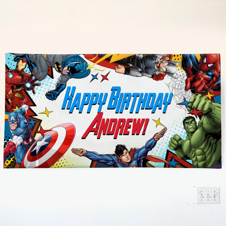 May include: A rectangular banner featuring various comic book superheroes including Iron Man, Batman, Thor, Spider-Man, Captain America, Hulk, and Superman. The text "Happy Birthday Andrew!" is printed in the center in blue and red lettering.
