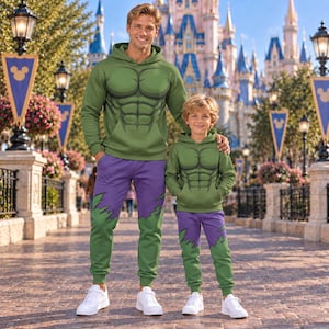 Puede incluir: Dos conjuntos a juego de sudaderas con capucha y pantalones deportivos que presentan un torso verde con un diseño muscular impreso y piernas moradas con un dobladillo verde dentado. Los conjuntos se combinan con zapatillas blancas.