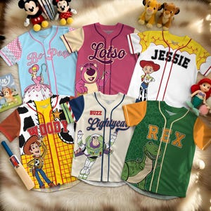 May include: Assortment of baseball jerseys featuring characters from the Toy Story franchise. Jerseys include Bo Peep, Lotso, Jessie, Woody, Buzz Lightyear, and Rex. Each jersey has a unique color scheme and character graphic.