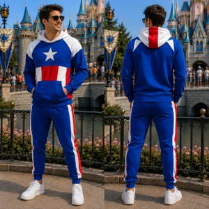 Pode incluir: Um conjunto de moletom com capuz e calças esportivas nas cores azul, branco e vermelho. O moletom apresenta uma estrela branca no peito, um bolso canguru e uma faixa vermelha no capuz. As calças possuem faixas laterais brancas e vermelhas.