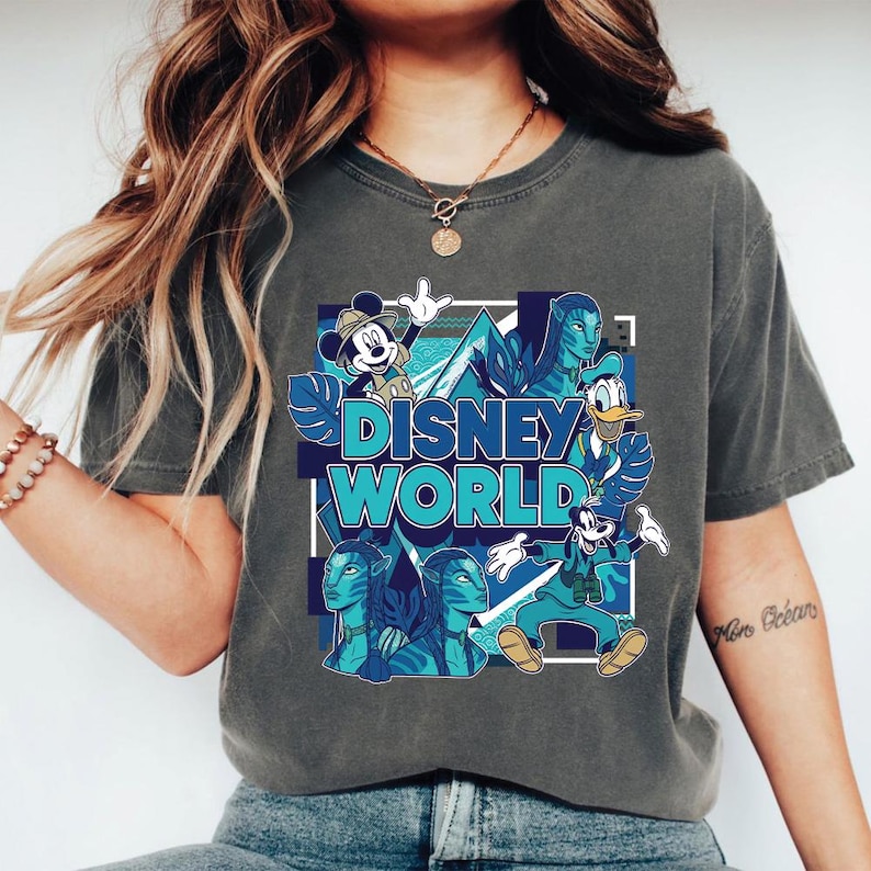 Puede incluir: Camiseta gris con un dise&ntilde;o de Disney World. El dise&ntilde;o incluye a Mickey Mouse, el Pato Donald, Goofy y personajes de Avatar, todos en tonos azules. Las palabras "Disney World" se muestran de forma destacada.
