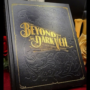 May include: A black book titled "Beyond the Dark Veil" with gold lettering and ornate embossed designs. The book's cover features the text "Post Mortem & Mourning Photography" and "The Thanatos Archive".