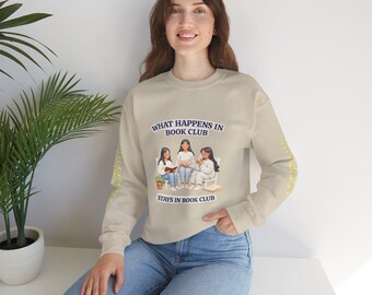 May include: Beige sweatshirt with the text "WHAT HAPPENS IN BOOK CLUB STAYS IN BOOK CLUB". The sweatshirt features an illustration of three women reading. The sleeves have a yellow floral pattern.