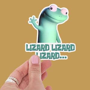 May include: A sticker with a cartoon lizard in teal, waving. The sticker has the text "Lizard Lizard Lizard..." in a playful font. The background is a mustard yellow colour. The sticker is held by a hand.