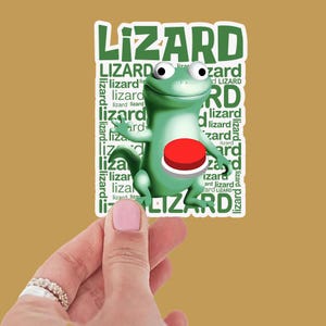 Könnte beinhalten: Ein grüner Cartoon-Eidechsen-Aufkleber mit dem Wort "LIZARD" in großen grünen Buchstaben. Die Eidechse hat einen roten Knopf auf der Brust. Der Hintergrund ist einfarbig beige.