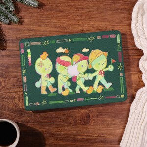 May include: A rectangular green mousepad featuring a whimsical illustration of four cartoon figures walking in a line. The figures are light green with various accessories, and are walking on a green field with yellow ducklings.