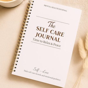 May include: A white spiral-bound journal with gold-colored coils, titled "The Self Care Journal." The cover includes the text "Mental Health Journal," "Time to Relax & Peace," and "Self-Love." A cup of coffee sits to the left.