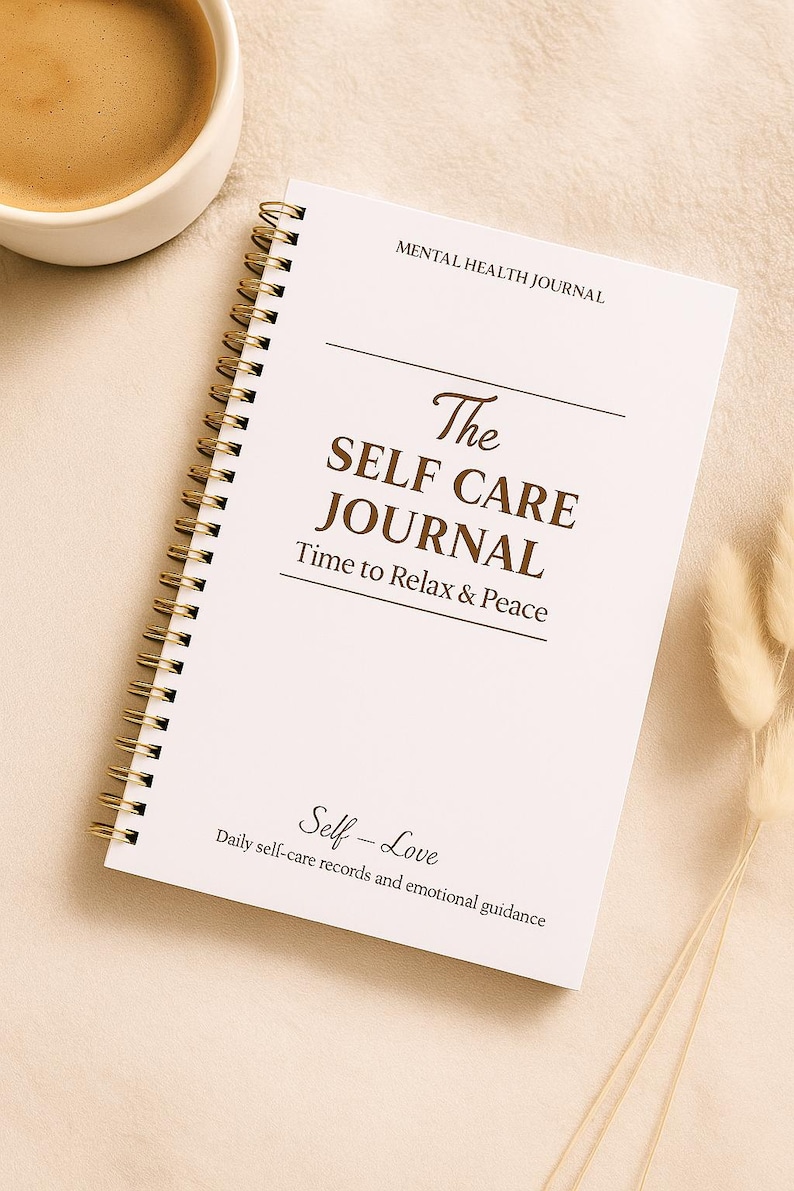 May include: A white spiral-bound journal with gold-colored coils, titled "The Self Care Journal." The cover includes the text "Mental Health Journal," "Time to Relax & Peace," and "Self-Love." A cup of coffee sits to the left.