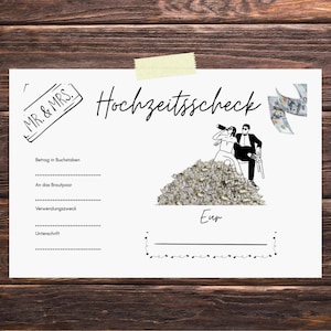 May include: A white rectangular wedding gift check featuring the text 'Hochzeitsscheck' and 'MR. & MRS.' with a graphic of a couple sitting on a pile of money. The form includes lines for 'Betrag in Buchstaben', 'An das Brautpaar', 'Verwendungszweck', 'Unterschrift', and 'Eur'.
