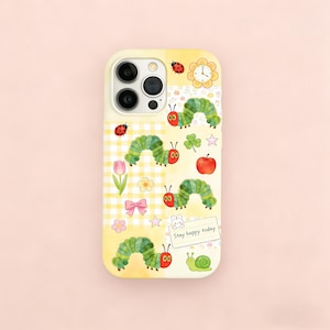 May include: A yellow phone case with a whimsical design featuring a green caterpillar, red ladybugs, a pink tulip, and the text "Stay happy today." The case has a playful, cartoonish aesthetic.