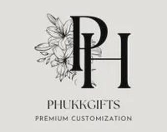 May include: A logo with the letters "PH" in a bold, black serif font, accompanied by a floral design on the left. Beneath the letters, the words "PHUKKGIFTS" and "PREMIUM CUSTOMIZATION" are written in a smaller, sans-serif font, against a light grey backdrop.