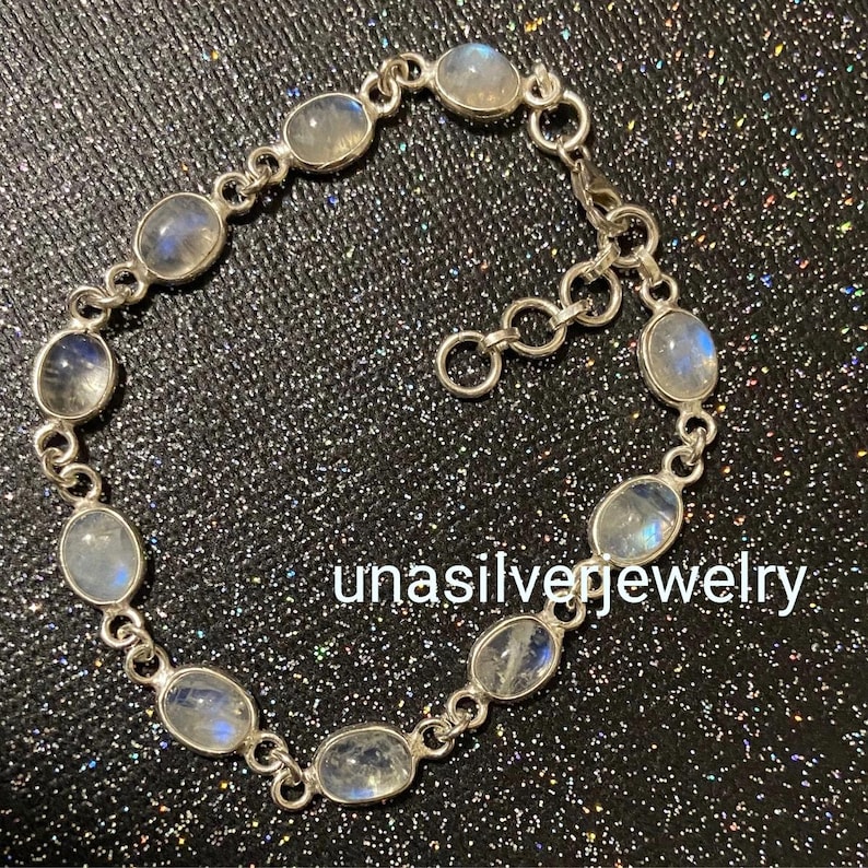 May include: A silver bracelet featuring oval-shaped moonstone gemstones. The bracelet is composed of interconnected links, with each link holding a moonstone. The text "unasilverjewelry" is visible on the image.