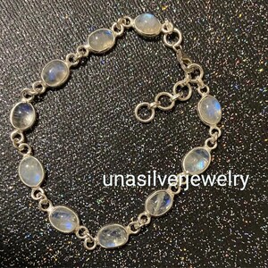May include: A silver bracelet featuring oval-shaped moonstone gemstones. The bracelet is composed of interconnected links, with each link holding a moonstone. The text "unasilverjewelry" is visible on the image.