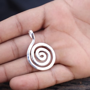 Puede incluir: Pendiente de plata con un diseño en espiral. El pendiente tiene un bucle en la parte superior para sujetarlo a una cadena.