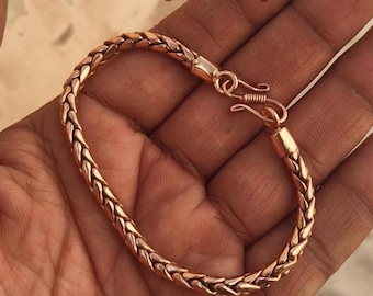 Puede incluir: Una pulsera de cadena trenzada de color cobre con un acabado metálico y un cierre de gancho. El texto Unasilverjewelry es visible en la esquina superior izquierda de la imagen. La pulsera tiene un patrón repetitivo de eslabones trenzados.