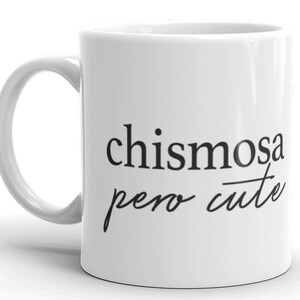 May include: White ceramic mug with black text that reads "chismosa pero cute".