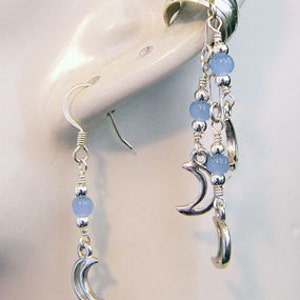 May include: Silver-toned earrings featuring a crescent moon design. One earring is a simple drop with a moon charm and blue beads. The other is a multi-strand design with moon charms and blue beads. The earrings are displayed on a white background.