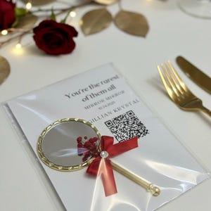 Pu&ograve; includere: Un piccolo specchio rotondo dorato con un manico decorativo, legato con un nastro rosso e una piccola composizione floreale. Lo specchio &egrave; confezionato con una carta che dice "You're the rarest of them all".