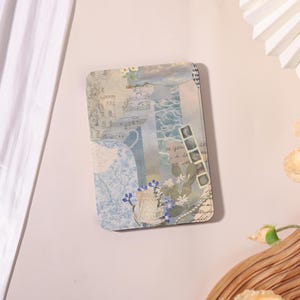 May include: A rectangular decorative card with a collage design. The collage features images of the sea, musical notes, and floral elements in shades of blue, white, and beige. The card has rounded corners and a vintage aesthetic.