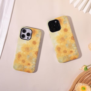 Op de afbeelding: Twee telefoonhoesjes met een gele zonnebloemontwerp. De hoesjes hebben een zwarte cameraran en een geelgroene achtergrond. De zonnebloemen zijn in verschillende maten en zijn verspreid over de hoes.