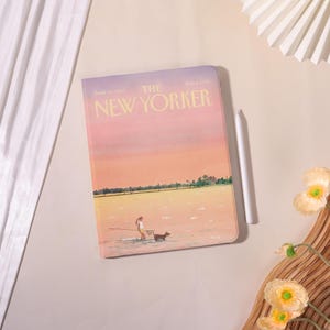 Könnte beinhalten: Eine Tablet-Hülle mit einer Illustration des Covers des Magazins "The New Yorker". Die Abbildung zeigt eine Person und einen Hund im Wasser unter einem rosa und gelben Himmel. Ein weißer Stift liegt neben der Hülle.