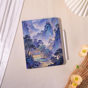 Puede incluir: Una funda rectangular para tableta con una vibrante ilustración digital de un paisaje montañoso con pinos, un pequeño edificio tradicional y un arroyo en tonos azules, morados y dorados, acompañada de un lápiz óptico de color blanco.