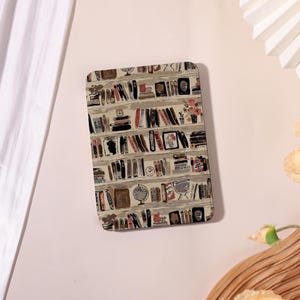 May include: Rectangular decorative tray featuring a watercolor illustration of a bookshelf filled with books, a globe, and a vase of flowers. The color palette includes beige, brown, red, and black.