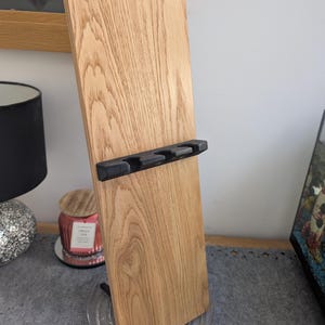 May include: A wooden stand with a black metal holder for four items. The stand is made of light wood with a natural grain pattern.