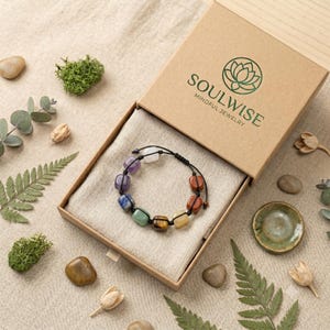 May include: A bracelet featuring multi-colored square gemstone beads on a black cord, presented in a tan cardboard box with the text SOULWISE MINDFUL JEWELRY printed on the lid. The beads include shades of purple, blue, green, brown, and white.