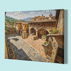 Könnte beinhalten: Leinwanddruck eines europäischen Stadtplatzes. Das Kunstwerk zeigt Gebäude mit gewölbten Durchgängen, Kopfsteinpflasterstraßen und Terrakotta-Dächern. Die Szene ist von Sonnenlicht durchflutet, mit blauem Himmel und fernen Bergen.