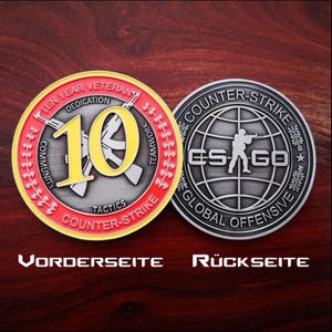 May include: Two commemorative coins. One coin has a red and yellow border with the text "TEN YEAR VETERAN" and "COUNTER-STRIKE". The other coin features a globe design with a silhouetted soldier and the text "COUNTER-STRIKE GLOBAL OFFENSIVE".