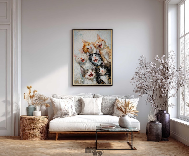 May include: A framed painting depicts a group of laughing cats with open mouths and various fur colors, including orange, black, and white. The artwork is displayed above a white sofa with decorative pillows, enhancing the room's decor.