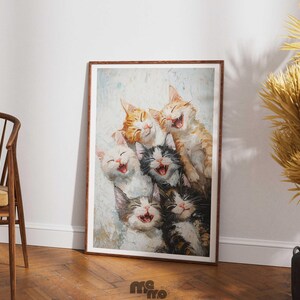 May include: A framed art print featuring a group of six laughing cats. The cats have various fur colors, including orange, black, white, and gray. The artwork is displayed in a room with a wooden floor and a chair.