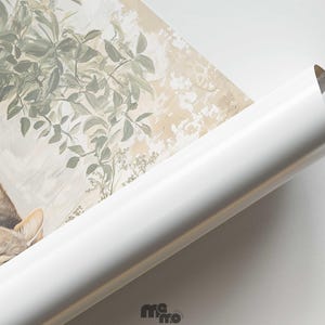 May include: A rolled-up art print featuring a sleeping tabby cat and botanical illustrations in muted tones. The print has a white border and a glossy finish. The cat's fur is a mix of brown, tan, and cream colors.