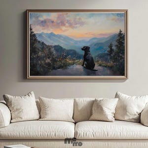 Pode incluir: Pintura de paisagem emoldurada que retrata um c&atilde;o preto a contemplar uma cordilheira ao p&ocirc;r do sol. A obra de arte tem uma moldura dourada e &eacute; exibida acima de um sof&aacute; creme com v&aacute;rias almofadas. A paleta de cores da pintura inclui azuis, laranjas e verdes.