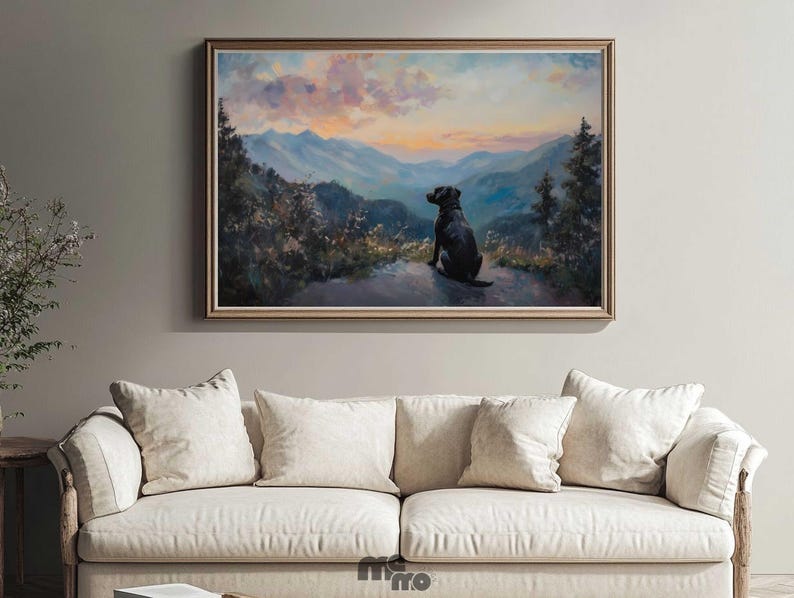 Pode incluir: Pintura de paisagem emoldurada que retrata um c&atilde;o preto a contemplar uma cordilheira ao p&ocirc;r do sol. A obra de arte tem uma moldura dourada e &eacute; exibida acima de um sof&aacute; creme com v&aacute;rias almofadas. A paleta de cores da pintura inclui azuis, laranjas e verdes.