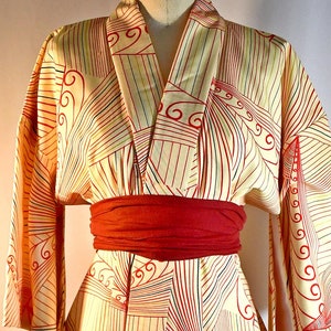 May include: A yellow and red patterned kimono with a red sash. The kimono has a geometric design with waves and lines.