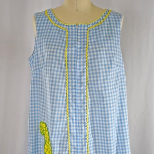 May include: A sleeveless blue and white gingham dress with yellow trim and a floral embroidery design. The dress has a zipper closure in the back.
