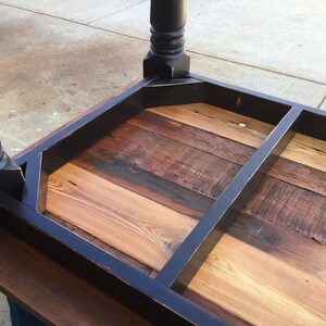May include: The underside of a black wooden table with a reclaimed wood top. The table has a simple, farmhouse style.