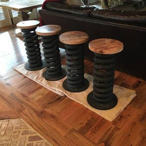 May include: Four industrial-style bar stools with wooden tops and black metal bases. The bases are made of stacked springs.