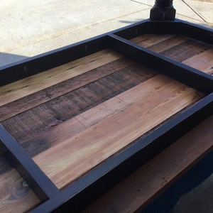 May include: A black wooden table top with a rectangular inset. The table top is made of reclaimed wood planks with a natural wood finish.