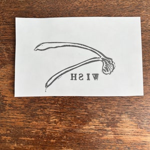 Könnte beinhalten: Eine Schwarzweißillustration eines gekrümmten Objekts mit dem darunter gedruckten Text "WISH".