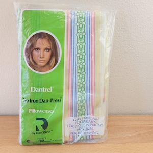 May include: A package of two standard pillowcases. The pillowcases have vertical stripes in pastel colors. The package is green and features a woman's portrait and the text "Dantrel No Iron Dan-Press Pillowcases". The pillowcases measure 20 x 26 inches.