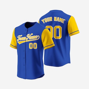 Könnte beinhalten: Ein blaues Baseball-Trikot mit gelben Ärmeln und Besatz. Auf der Vorderseite des Trikots steht der Text "Team Name" in gelber Schrift über der Nummer "00". Auf der Rückseite des Trikots steht der Text "YOUR NAME" über der Nummer "00".