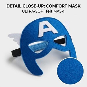 May include: A blue felt mask with a white "A" and white wing accents. The mask has a black elastic strap and is labeled "DETAIL CLOSE-UP: COMFORT MASK ULTRA-SOFT felt MASK". The mask is designed for comfort and is made of soft felt.